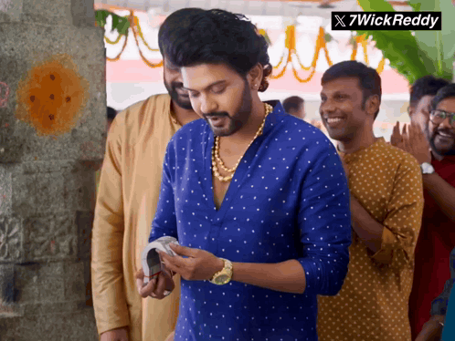 a man in a blue shirt is standing in a crowd with a 7wick reddy logo in the corner