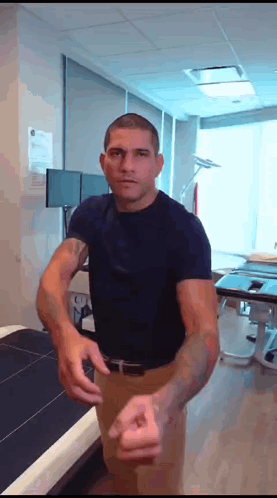 A Man In A Blue Shirt Is Standing In A Room With His Arms Outstretched GIF