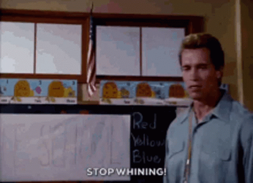 A Man In A Blue Shirt Is Standing In Front Of A Blackboard That Says Stop Whining . GIF