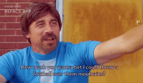 A Man In A Blue Shirt Is Standing In Front Of A Door And Talking To Someone . GIF