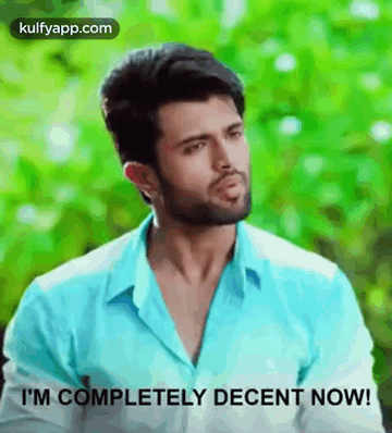 A Man In A Blue Shirt Is Standing In Front Of A Green Background And Says `` I 'M Completely Decent Now ! '' GIF