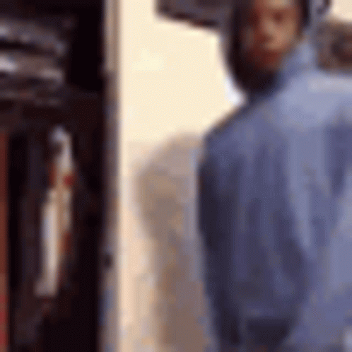 A Man In A Blue Shirt Is Standing In Front Of A Locker . GIF