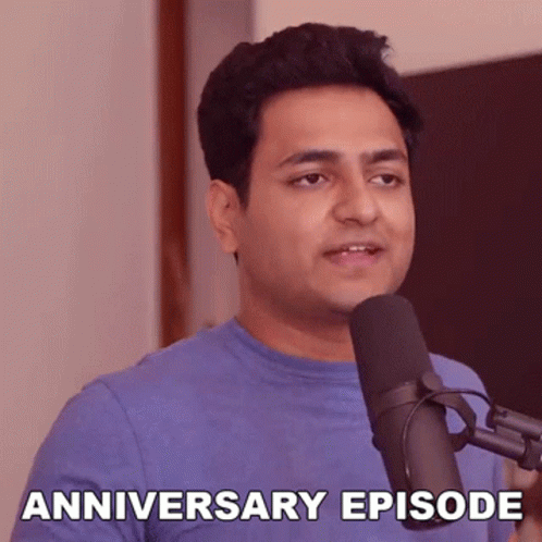 A Man In A Blue Shirt Is Standing In Front Of A Microphone And Says Anniversary Episode . GIF