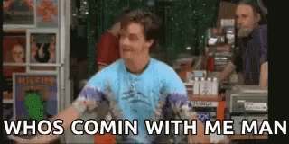 A Man In A Blue Shirt Is Standing In Front Of A Record Store . GIF