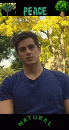 A Man In A Blue Shirt Is Standing In Front Of Trees With The Word Peace Written On It GIF