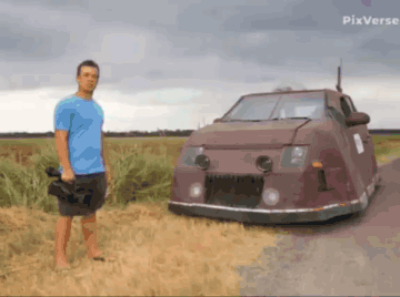 A Man In A Blue Shirt Is Standing Next To A Car With Pixverse Written In The Corner GIF