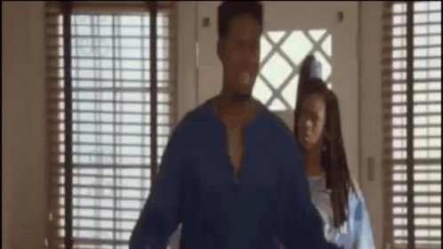 A Man In A Blue Shirt Is Standing Next To A Woman In A Blue Dress GIF