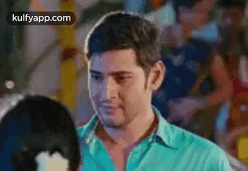 A Man In A Blue Shirt Is Standing Next To A Woman In A Crowded Room . GIF