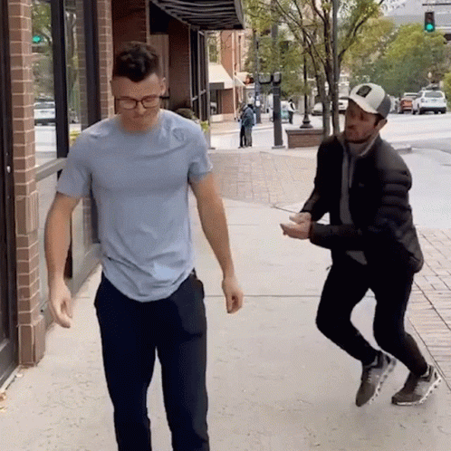 A Man In A Blue Shirt Is Standing Next To Another Man GIF