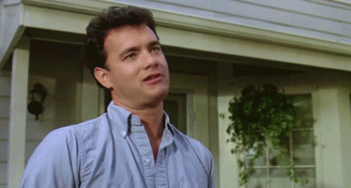 A Man In A Blue Shirt Is Standing On A Porch GIF