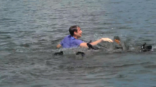 A Man In A Blue Shirt Is Swimming In The Ocean GIF