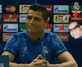 A Man In A Blue Shirt Is Talking Into A Microphone In Front Of A Wall With Advertisements For Lays And Sony GIF