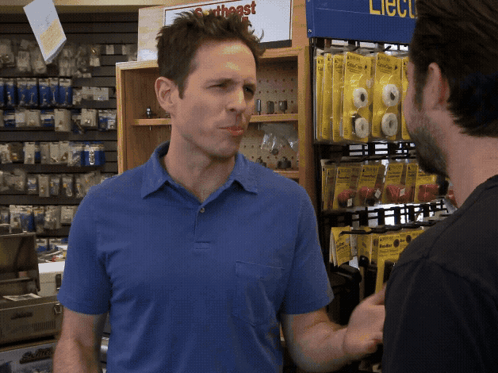 A Man In A Blue Shirt Is Talking To Another Man In Front Of A Sign That Says ' Southeast ' GIF