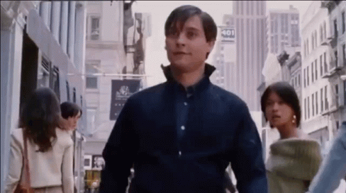 A Man In A Blue Shirt Is Walking Down A City Street With A Woman . GIF