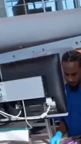 A Man In A Blue Shirt Is Working On A Computer . GIF