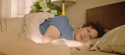 A Man In A Blue Shirt Laying In Bed GIF