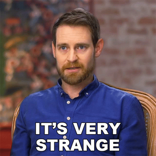 A Man In A Blue Shirt Says " It 'S Very Strange " While Sitting In A Chair GIF