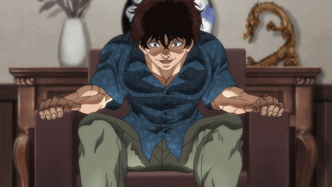 A Man In A Blue Shirt Sits In A Chair With His Hands Outstretched GIF