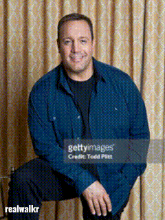 A Man In A Blue Shirt Sits In Front Of A Curtain GIF