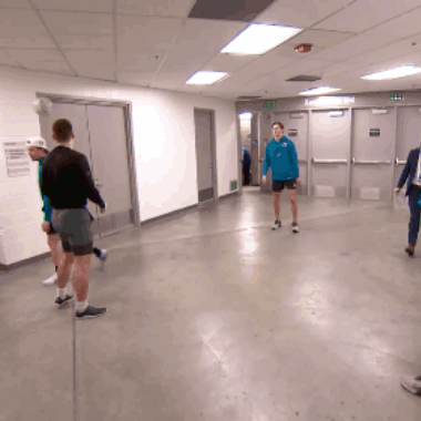 A Man In A Blue Shirt Stands In A Hallway GIF