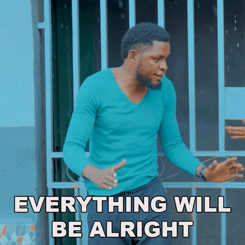 a man in a blue shirt stands in front of a fence with the words everything will be alright