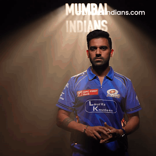 A Man In A Blue Shirt Stands In Front Of A Mumbai Indians Sign GIF