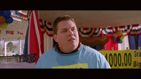 A Man In A Blue Shirt Stands In Front Of A Sign That Says ' Grand Prize ' GIF