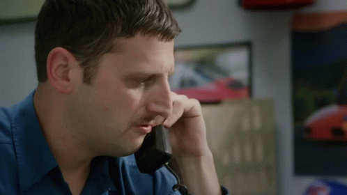 A Man In A Blue Shirt Talking On A Phone GIF