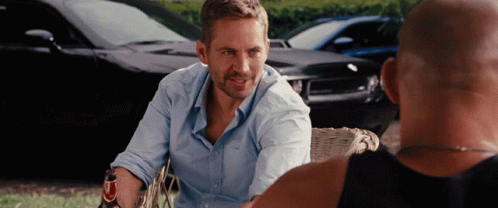 A Man In A Blue Shirt Talks To Another Man In A Black Tank Top GIF