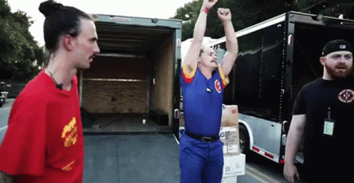 A Man In A Blue Shirt With The Letter C On It Is Standing In Front Of A Truck GIF