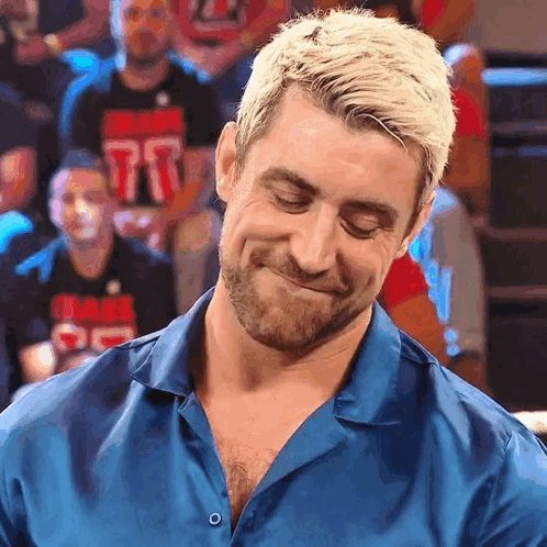 A Man In A Blue Shirt With The Number 77 On His Shirt Is Smiling GIF