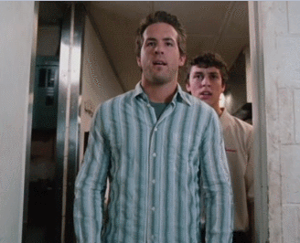 A Man In A Blue Striped Shirt Stands In A Hallway GIF