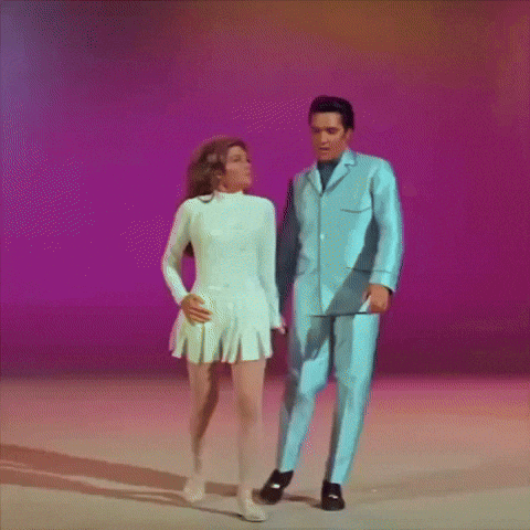 A Man In A Blue Suit And A Woman In A White Dress Are Dancing Together GIF
