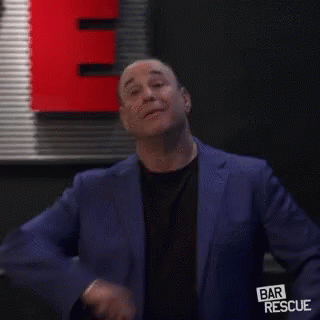 Man In Blue Suit And Black Shirt In Front Of Red Sign GIF