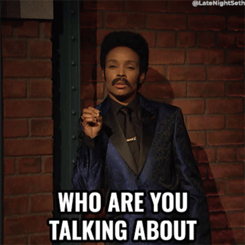 A Man In A Blue Suit And Black Tie Is Holding A Cigarette And Says Who Are You Talking About GIF