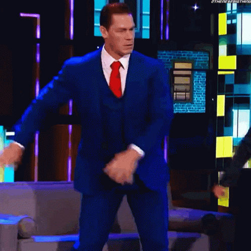 A Man In A Blue Suit And Red Tie Is Dancing On A Television Show . GIF