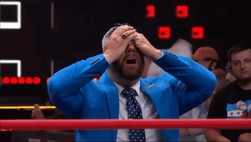 A Man In A Blue Suit And Tie Is Covering His Eyes GIF