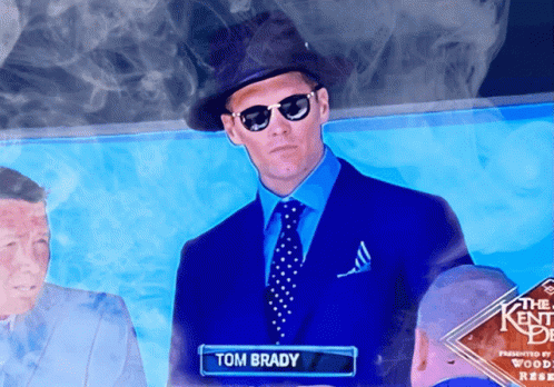 A Man In A Blue Suit And Tie With The Name Tom Brady GIF