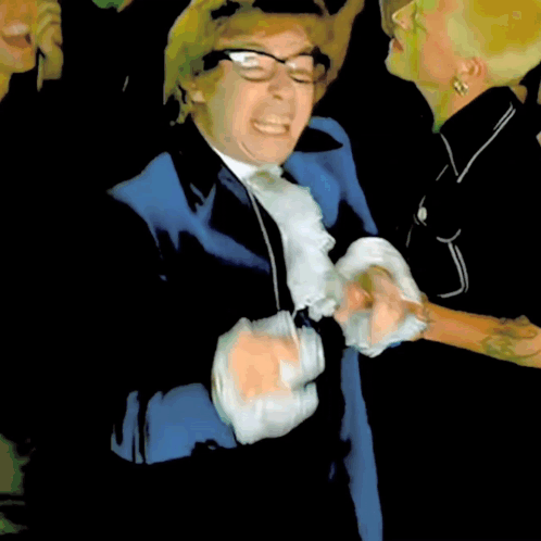 A Man In A Blue Suit And White Tie Is Making A Face GIF