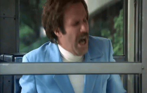 A Man In A Blue Suit And White Turtleneck Is Screaming While Looking Out Of A Window . GIF