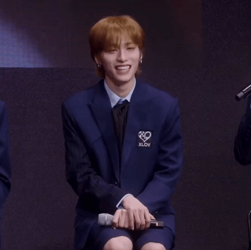 A Man In A Blue Suit Has The Word Xlov On The Front Of His Jacket GIF