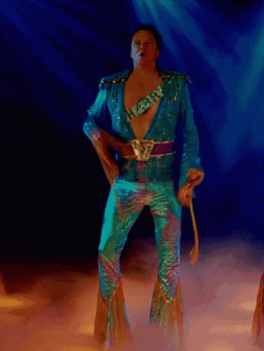 A Man In A Blue Suit Is Dancing In A Dark Room GIF