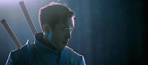 A Man In A Blue Suit Is Holding Two Swords In His Back . GIF