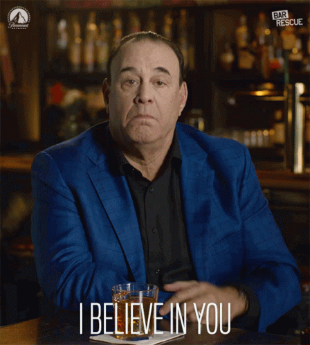 A Man In A Blue Suit Is Sitting At A Bar And Says I Believe In You GIF