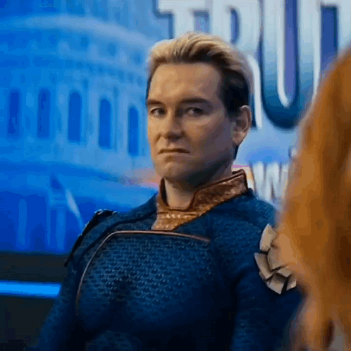 A Man In A Blue Suit Is Sitting In Front Of A Building And Looking At Another Man . GIF