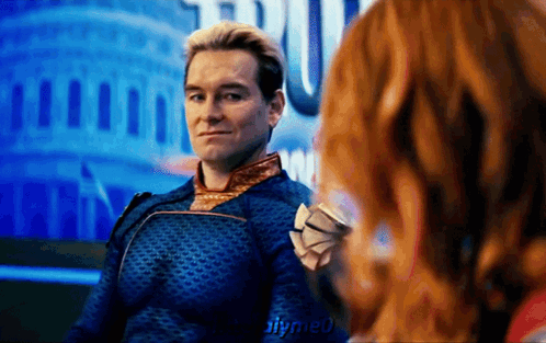 A Man In A Blue Suit Is Sitting Next To A Woman With Red Hair .. GIF