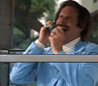 A Man In A Blue Suit Is Smoking A Cigarette While Talking On A Cell Phone GIF