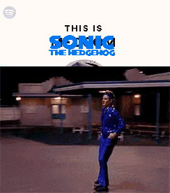 A Man In A Blue Suit Is Standing In Front Of A Building With The Words This Is Sonic The Hedgehog Above Him GIF