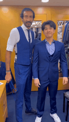 A Man In A Blue Suit Is Standing Next To Another Man In A White Shirt GIF