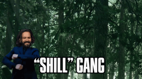 A Man In A Blue Suit Says " Shill Gang " In Front Of A Forest GIF